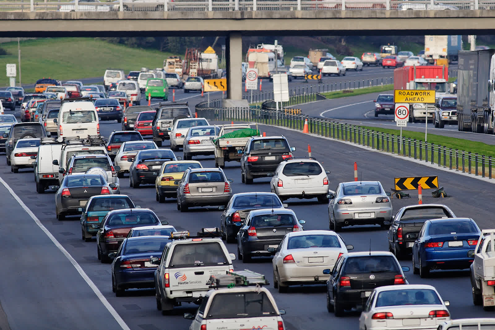 Peak-hour traffic queued on a Melbourne freeway, with a roadwork-ahead sign visible
